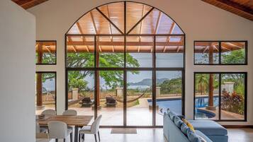 A spacious room with a large arched window, a pool, and a seating area.