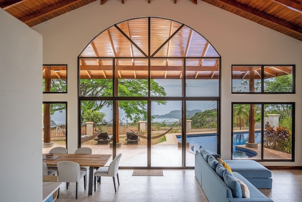 A spacious room with a large arched window, a pool, and a seating area.