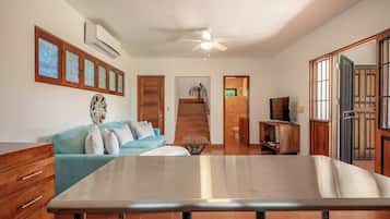 A modern living room with a sofa, a dining table, and a TV.