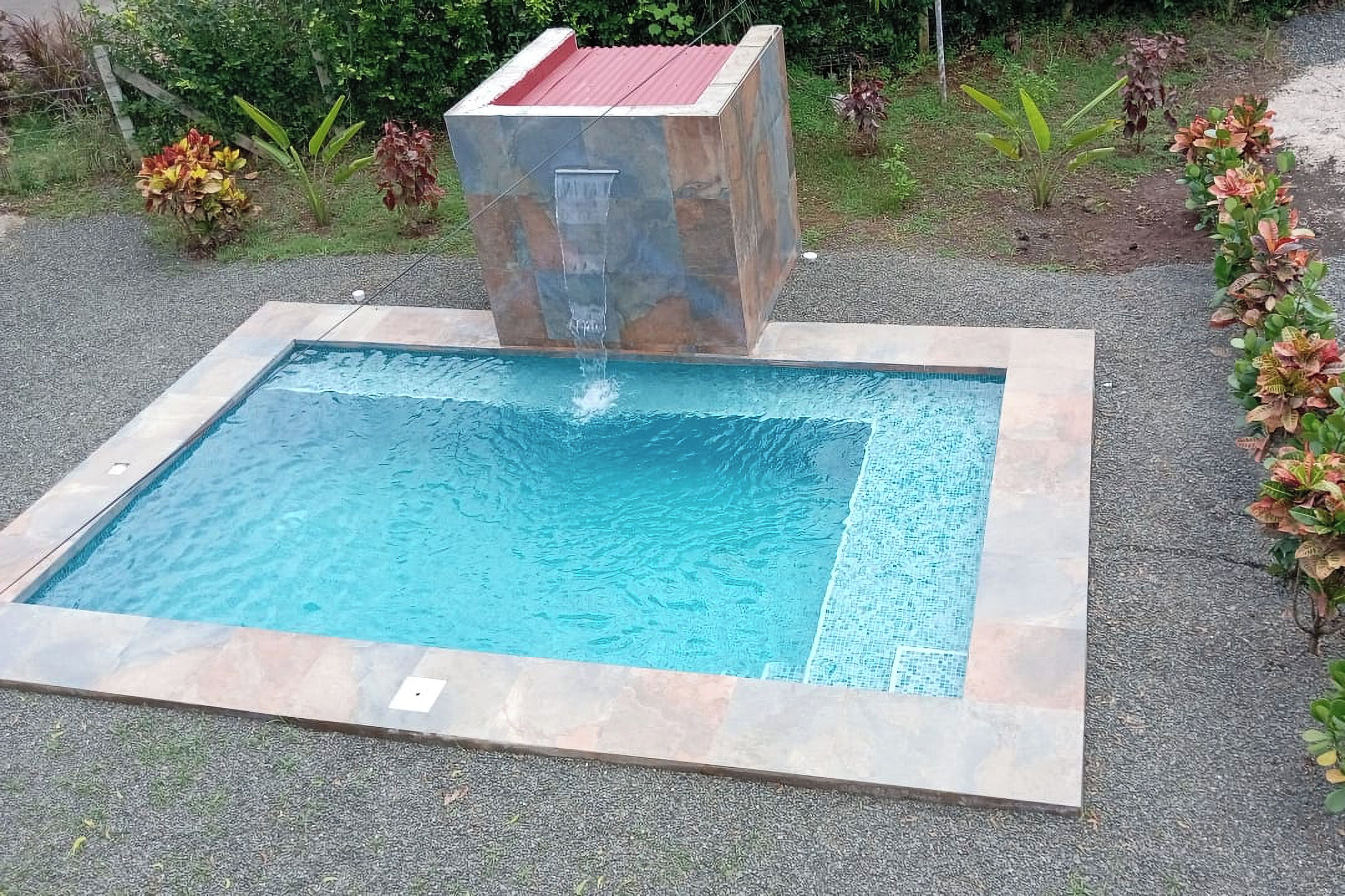 A rectangular swimming pool with a central water feature.