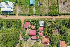 An aerial view of a residential area with multiple houses, a dirt road, and surrounding greenery. - Santa Cruz Group Getaway w/ Pool: Walk to Beach (Veintisiete de Abril)