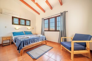 A bedroom with a bed, a chair, a nightstand, and a window with curtains. - Santa Cruz Group Getaway w/ Pool: Walk to Beach (Veintisiete de Abril)
