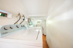 A laundry area with a Whirlpool washer and dryer, a water heater, and a window with a view of greenery.