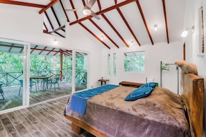 A bedroom with a large bed, a ceiling fan, and a view of greenery outside. - Secluded Ojochal Studio w/ Trails & Pool Access! (Ciudad Cortés)