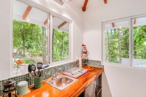 A kitchen with a wooden countertop, a stainless steel sink, and a window overlooking a forest. - Secluded Ojochal Studio w/ Trails & Pool Access! (Ciudad Cortés)