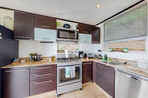 A modern kitchen with dark cabinetry, stainless steel appliances, and a granite countertop.