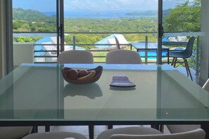A dining table with chairs, a bowl of fruit, and a striped placemat. - Playas del Coco Home w/ Ocean-views, Deck, Pool (Sardinal)