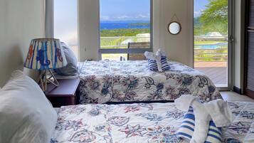 Un dormitorio con dos camas, una lámpara y vistas a una piscina y follaje.
