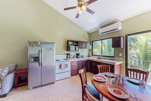 A compact kitchen with a refrigerator, stove, and dining area with chairs and a table set for two. - Playa Ocotal Condo w/ Pool: Walk to the Beach! (Sardinal)