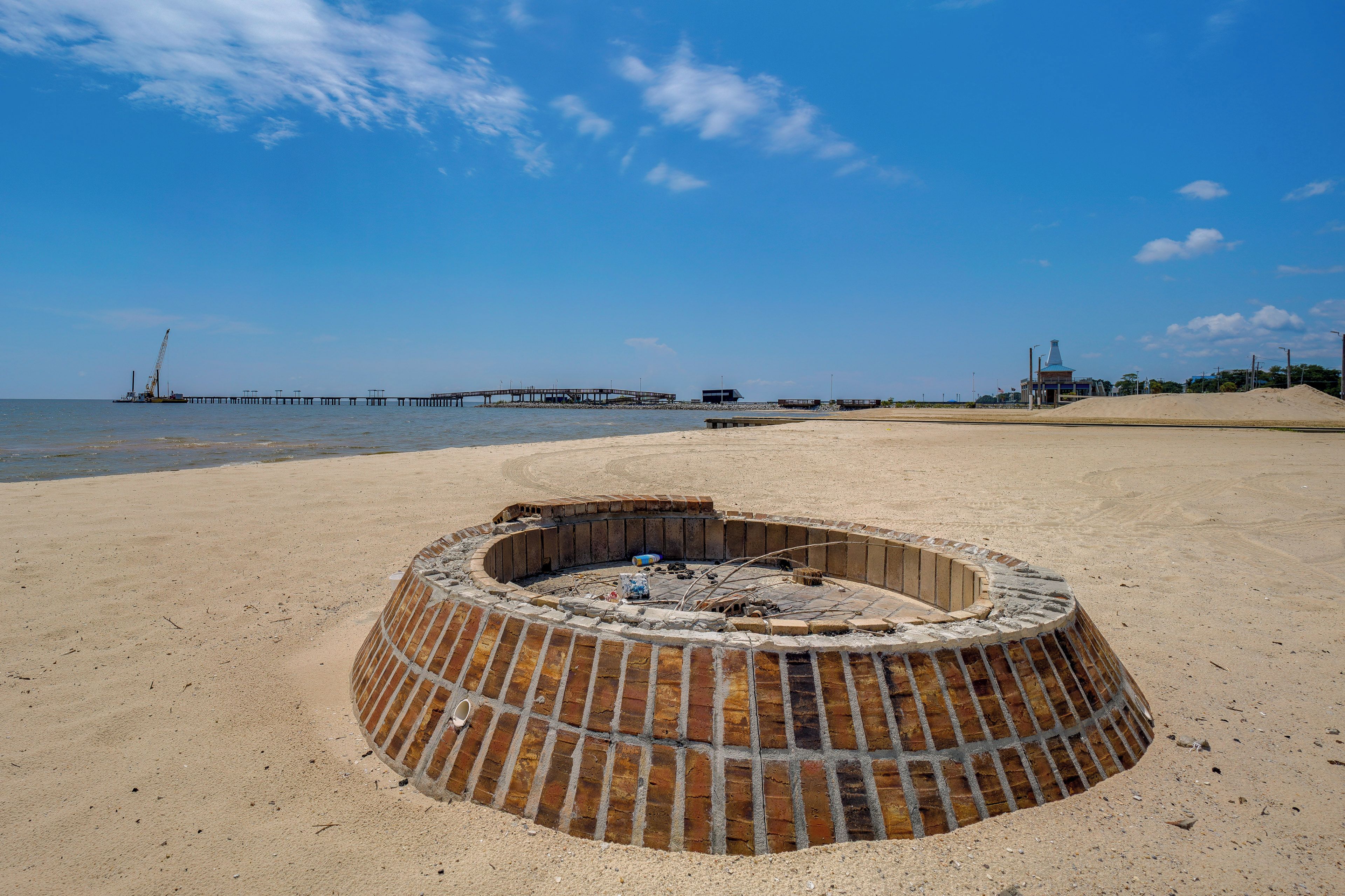 Una playa con un pozo de fuego circular de ladrillo en primer plano.