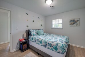 Quarto com cama, mesa de cabeceira, janela e luminária no teto.