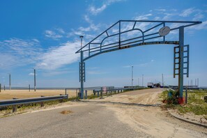 A beach entrance with a metal archway, a dirt path, and a fence. - 1 Mi to Beach! Family-friendly Waveland Home (Waveland)