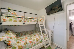 A bunk bed with a ladder, a television mounted on the wall, and a door leading to a bathroom.