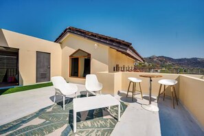 A rooftop terrace with a table and chairs, a door, and a view of a hilly landscape. - Playa Hermosa Penthouse: Ocean Views, 2 Pools (Sardinal)