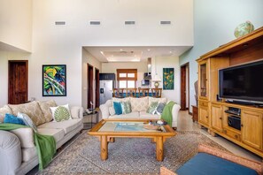 A spacious living room with a sofa, coffee table, and TV stand. - Playa Hermosa Penthouse: Ocean Views, 2 Pools (Sardinal)