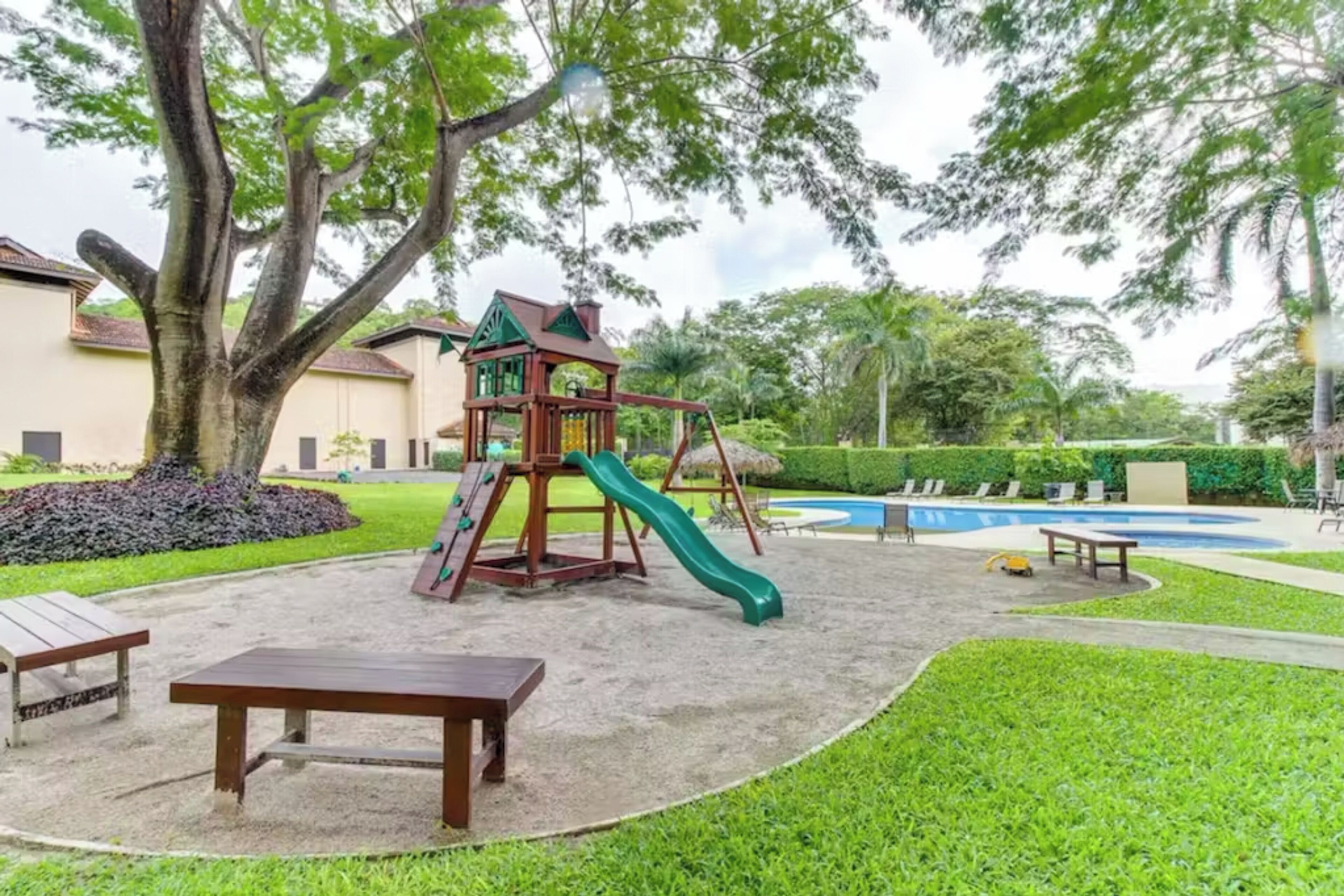 A playground with a slide and climbing structure, a pool, and a picnic table.