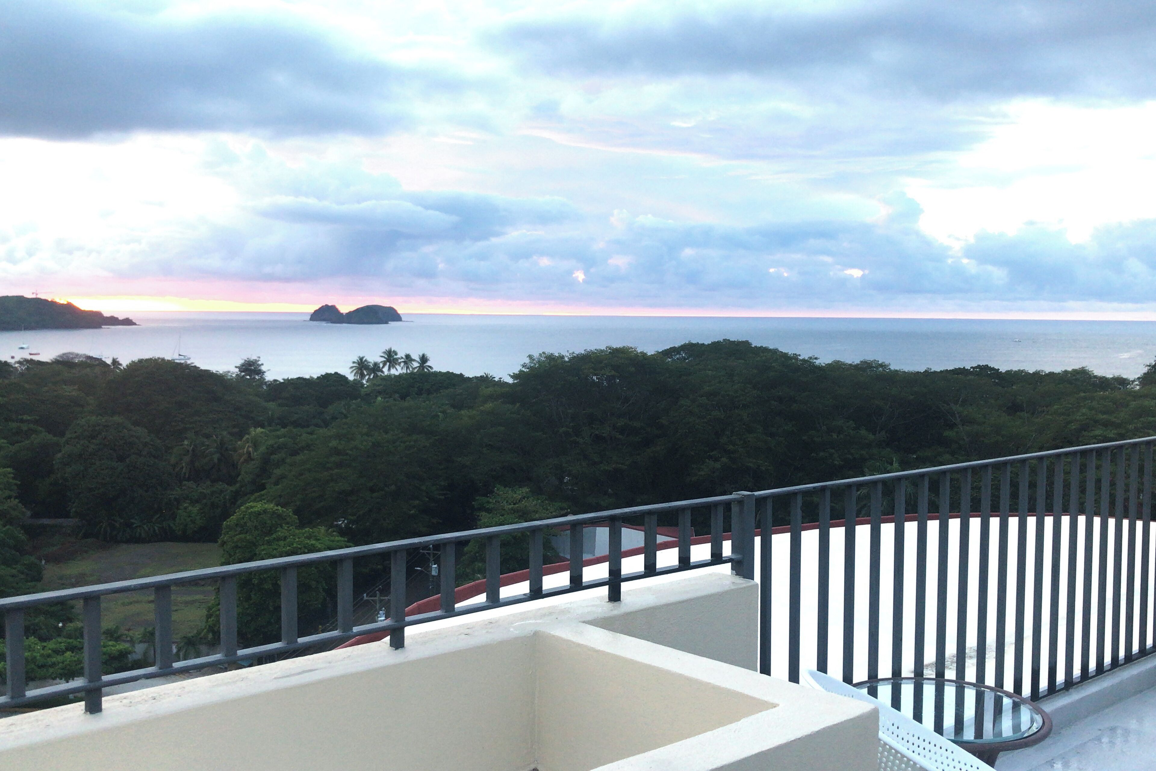 A balcony with a view of the sea and a distant island.
