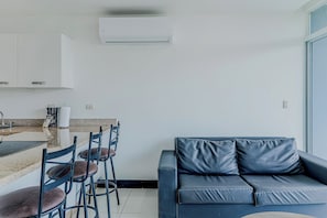 A modern living space with a kitchen area, a dining table with chairs, and a sofa with cushions. - Ocean-view Stay, El Roble Marina & Pool Access (Puntarenas)