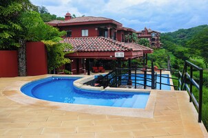 Piscina com um edifício de telhado vermelho ao fundo.