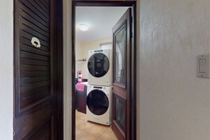 A laundry room with two stacked washing machines and a fire extinguisher.
