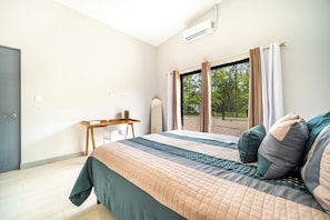 Un dormitorio con una cama, un escritorio y una ventana con cortinas.