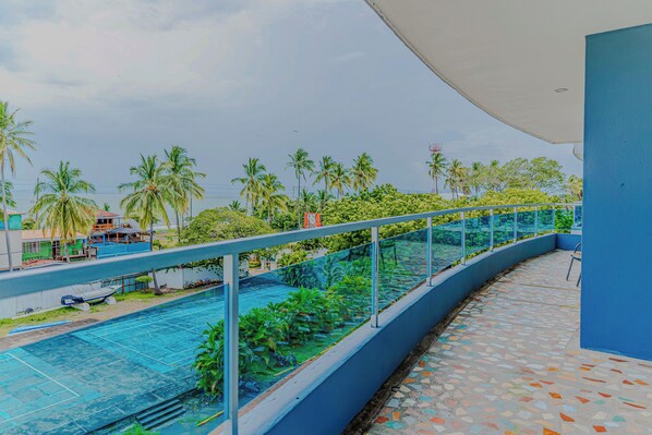 A pool area with a glass balustrade, surrounded by greenery and palm trees. - Puerto Azul Marina, Pool & On-site Dining (Puntarenas)