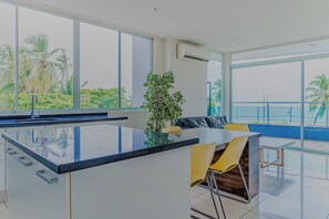 A modern kitchen with a central island, large windows, and a view of palm trees. - Puerto Azul Marina, Pool & On-site Dining (Puntarenas)
