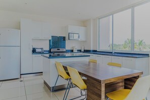 A modern kitchen with a central island, white cabinets, and a view of palm trees through the window. - Puerto Azul Marina, Pool & On-site Dining (Puntarenas)