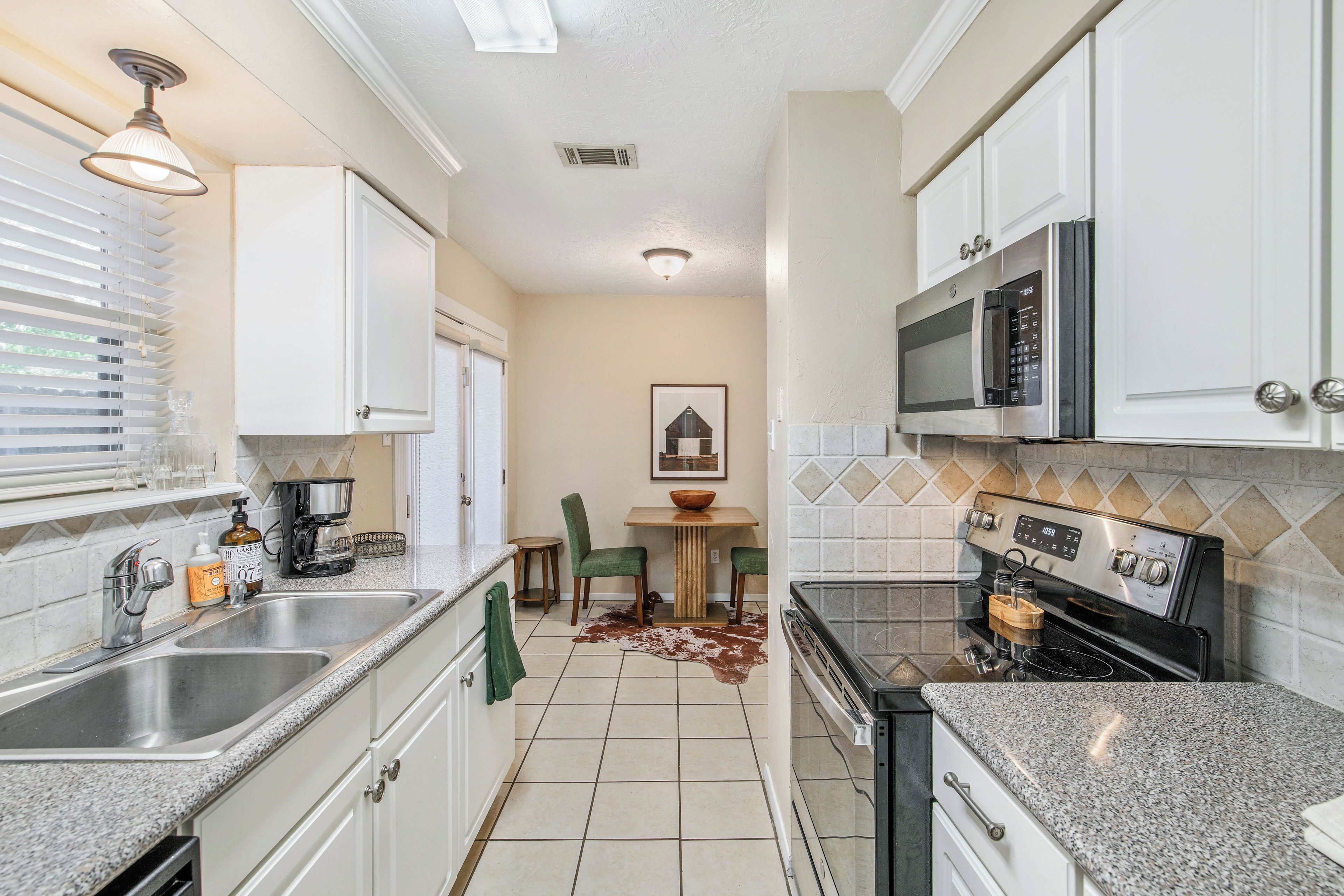 A modern kitchen with stainless steel appliances, a coffee maker, and a dining area with a table and chairs.