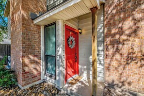 A red door with a wreath, a white porch, and a brick wall. - 2 Mi to Campus! College Station Condo w/ Pool (College Station)