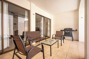 A balcony with seating, a grill, and a view of the interior.