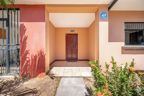 A building entrance with a door marked 'BENVENUTO!' and a sign indicating 'Protegido por ADT'.