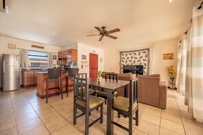 A modern kitchen with a refrigerator, stove, and dining area with chairs and a table.
