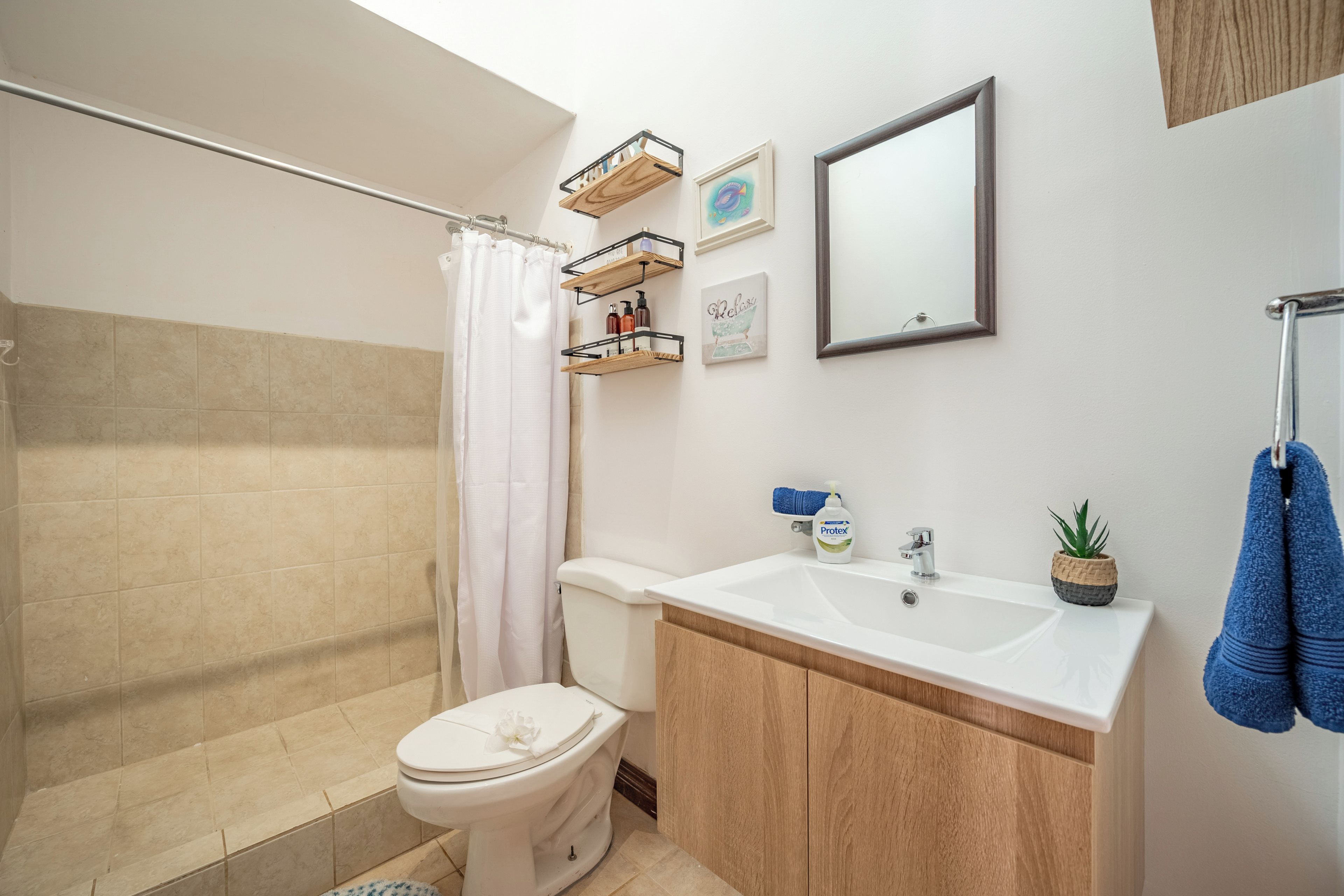 Ein Badezimmer mit Dusche, Toilette, Waschbecken und Spiegel.