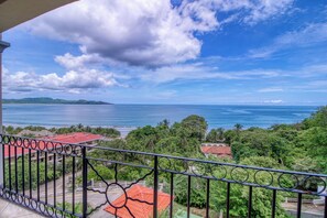 Ein Balkon mit Blick auf eine Küstenlandschaft, inklusive Strand und Meer.