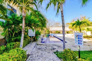 A pool area with a sign indicating rules and a pathway leading to it. - Stunning 2BR Oceanview 4th-floor Balcony (Cabo Velas)