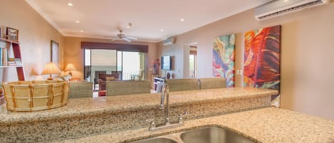 Una cocina con encimeras de granito, pileta de acero inoxidable y ventilador de techo.