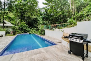 A swimming pool with a tiled edge, a barbecue grill, and a white wall with a window. - Off-grid Ojochal Studio w/ Pool & Trail Access! (Ciudad Cortés)