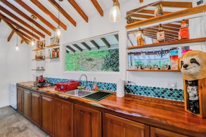 A kitchen with wooden cabinets, a red sink, and a window with a green view. - Off-grid Ojochal Studio w/ Pool & Trail Access! (Ciudad Cortés)