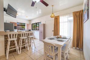 Eine moderne Küche mit Essbereich, einem an der Wand montierten Fernseher und einem Deckenventilator.