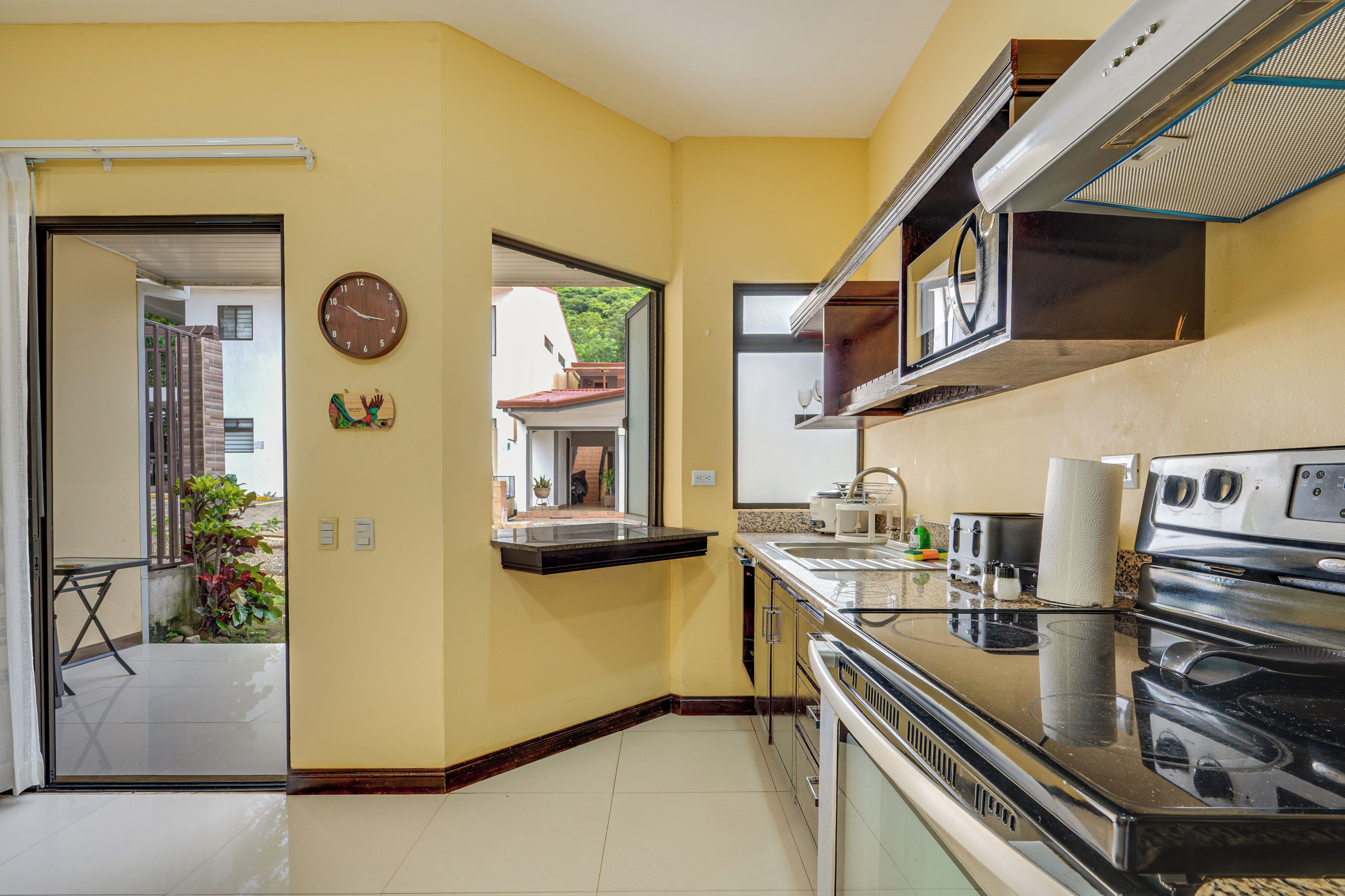 Una cocina con estufa, microondas y un reloj en la pared.