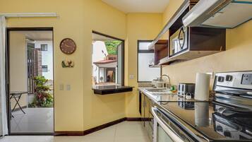 Una cocina con estufa, microondas y un reloj en la pared.