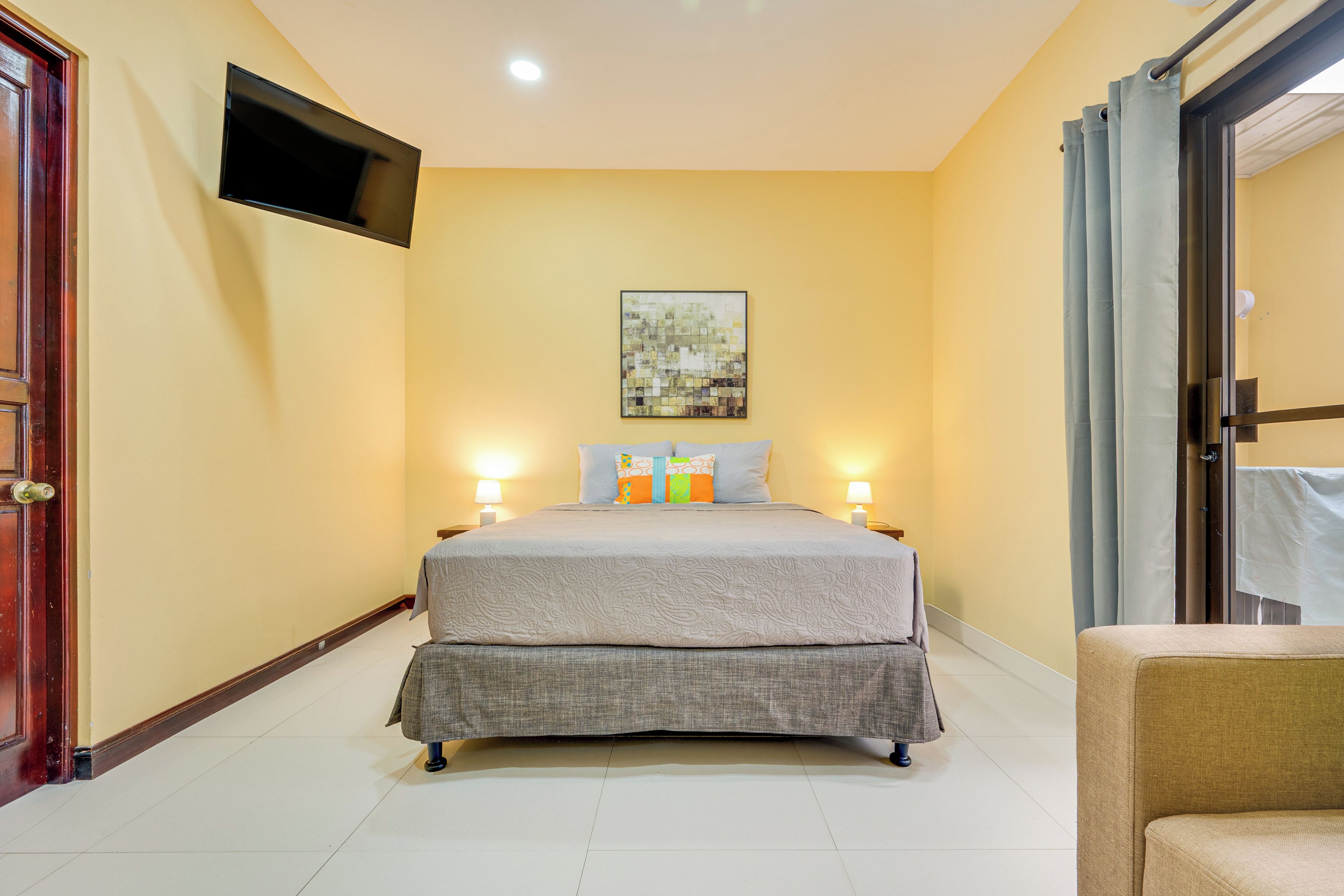 Habitación de hotel con una cama, un televisor de pantalla plana en la pared y un cuadro sobre la cama.