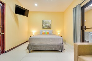 A hotel room with a bed, a flat-screen TV mounted on the wall, and a painting above the bed.