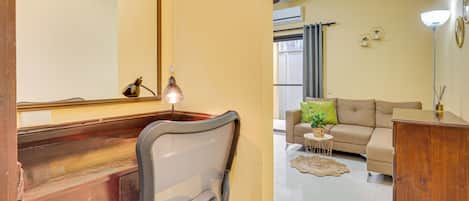 A room with a wooden desk, a chair, a sofa, and a small table with a plant.