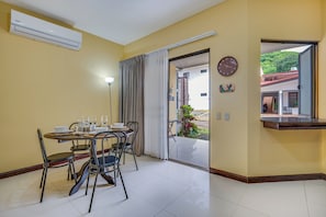 A dining area with a table set for four, chairs, a clock, and a view through an open door.