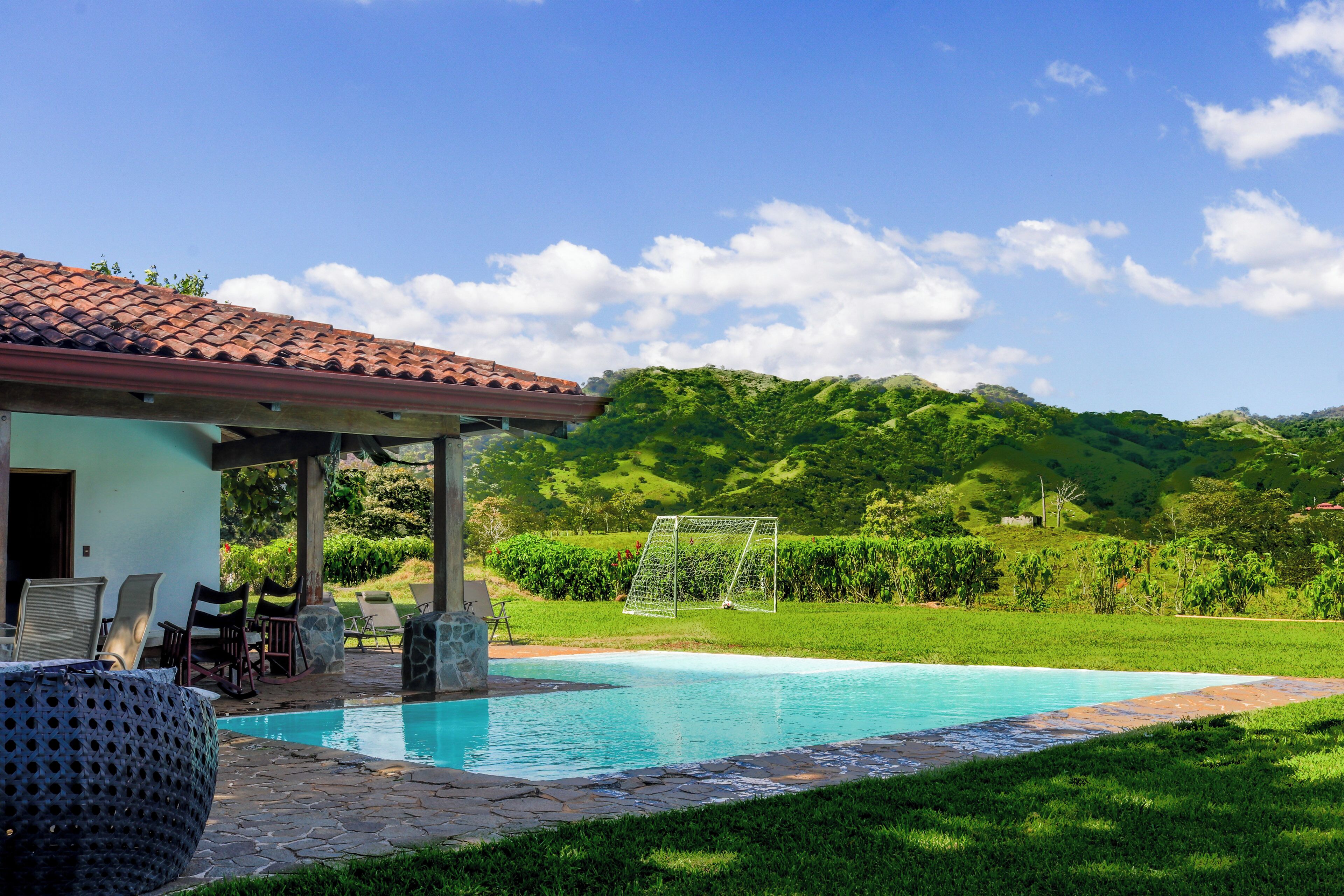 A pool area with a pergola, lounge chairs, and a soccer goal.