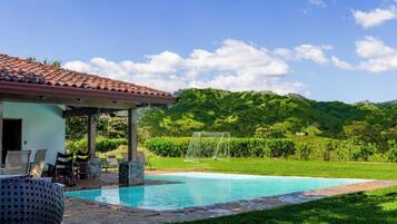 A pool area with a pergola, lounge chairs, and a soccer goal.