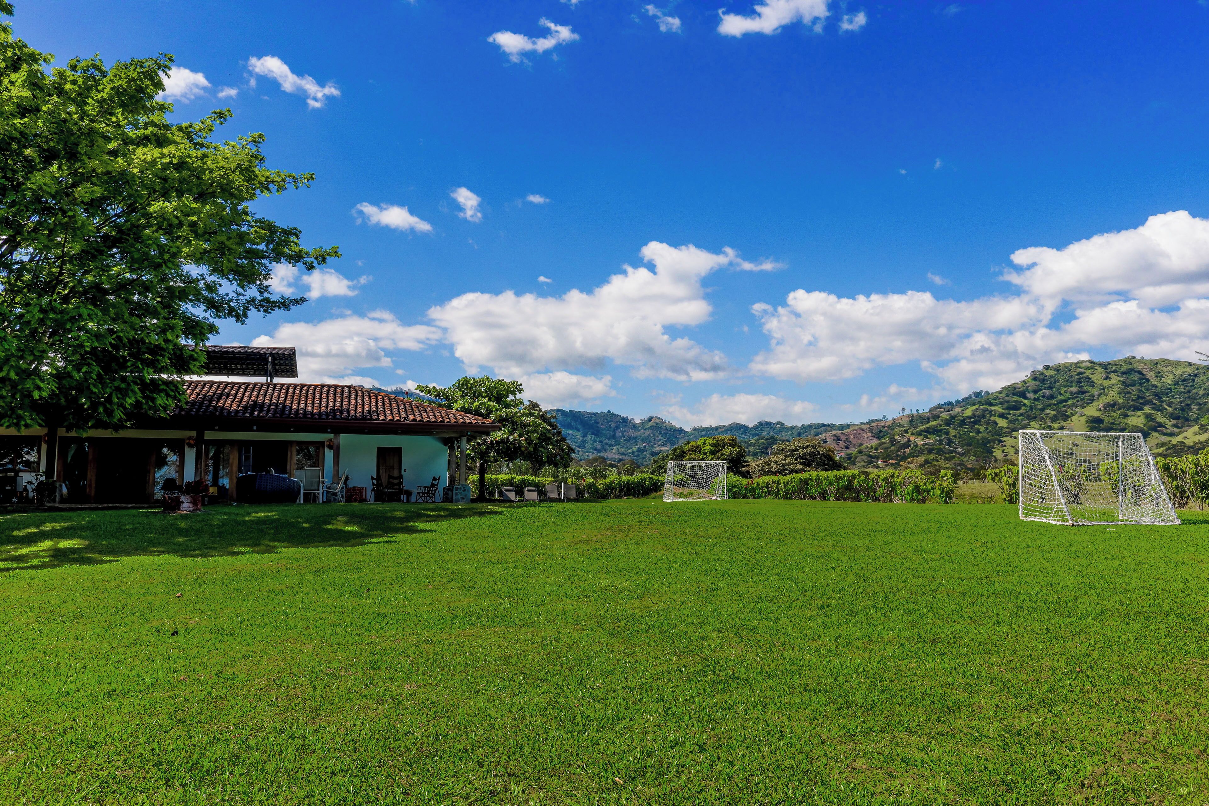 A grassy field with a building and a soccer goal.