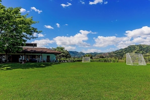 A grassy field with a building and a soccer goal.